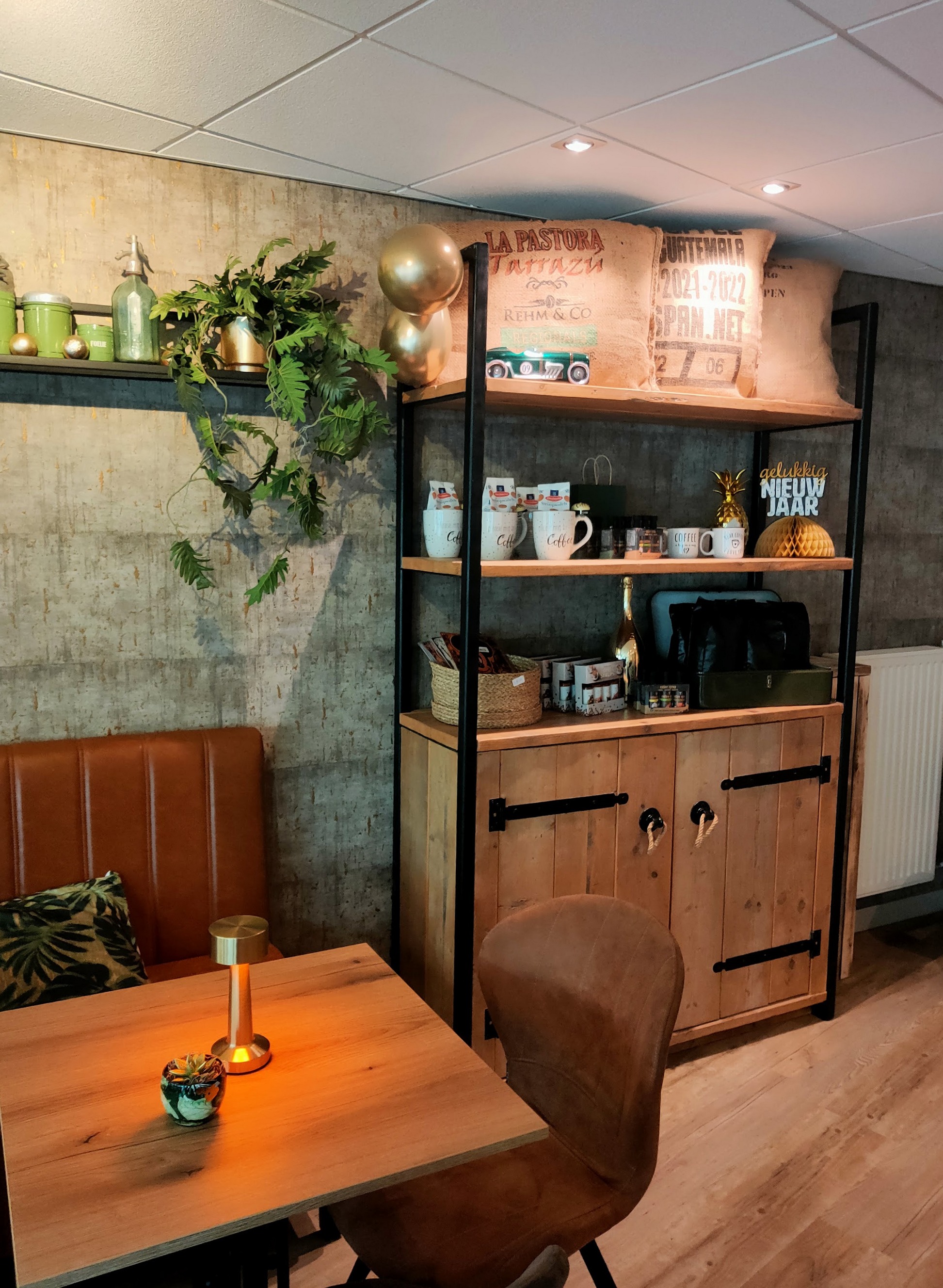 Een ronde tafel en de koffiehoek met houten planken en groene details